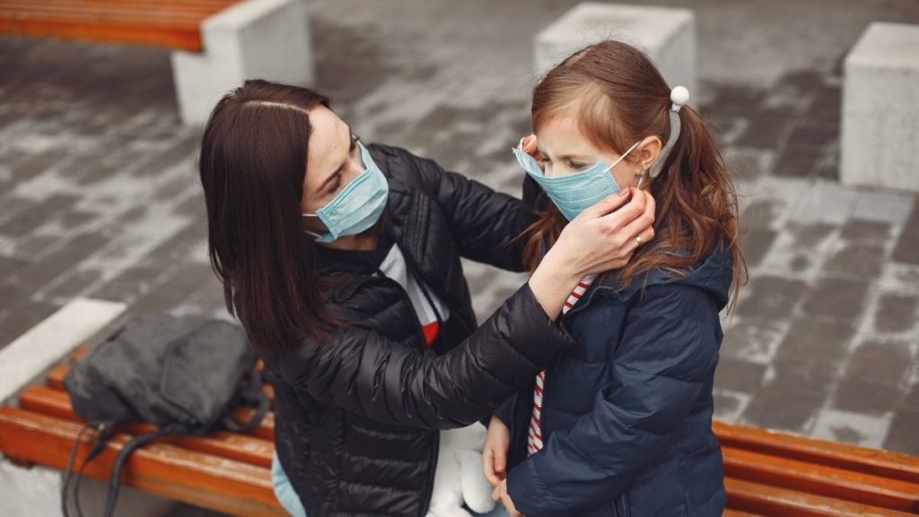 Mother adjusts daughter's mask